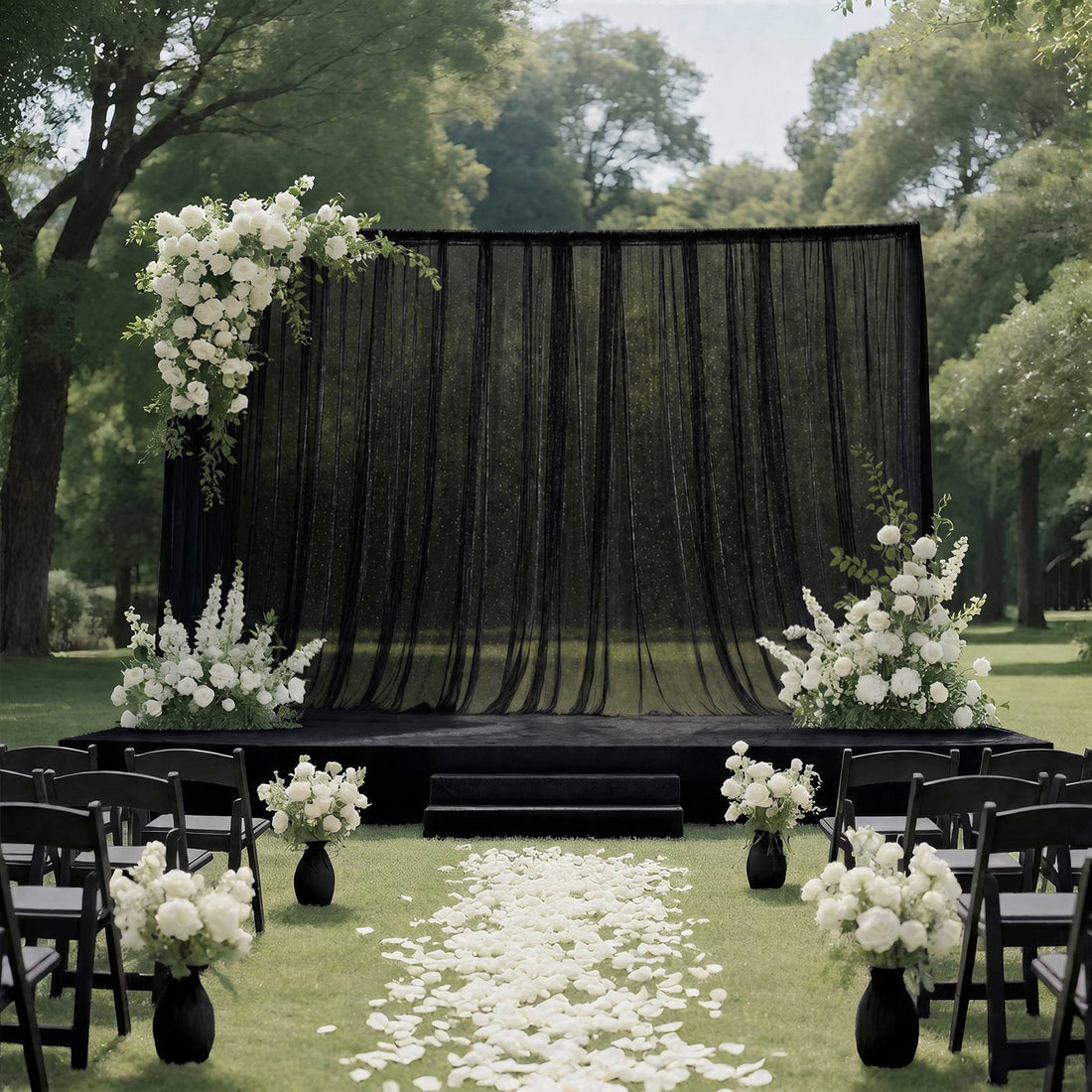 Elegant outdoor wedding ceremony setup with black drape backdrop and white florals