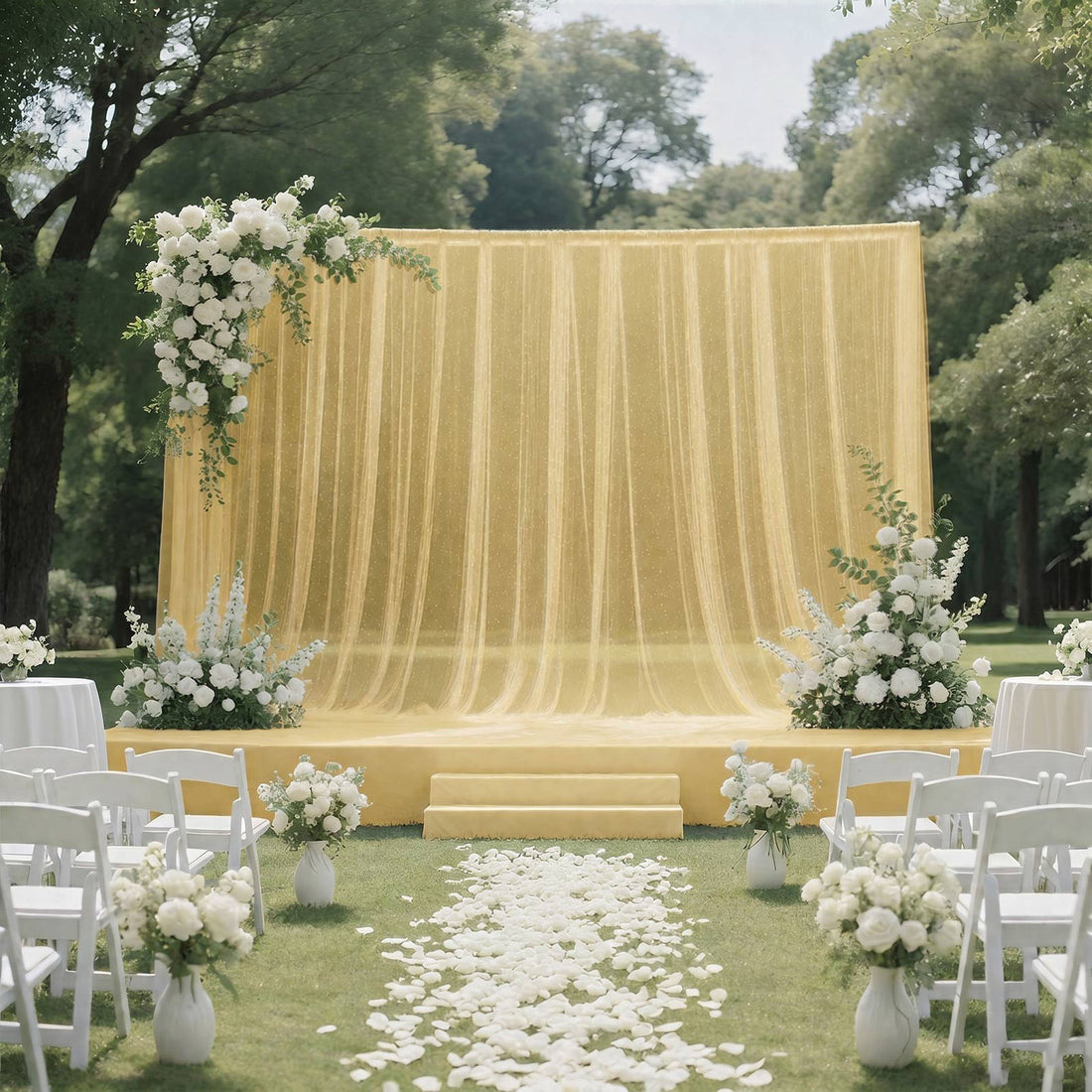 Outdoor wedding ceremony setup with yellow draped backdrop and white floral arch