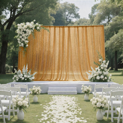 Outdoor wedding ceremony setup with gold backdrop, white flowers, and aisle petals