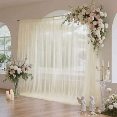 Elegant wedding backdrop with floral arch, sheer curtain, and candles