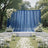 Outdoor wedding ceremony setup with blue drapes, white flowers, and chairs