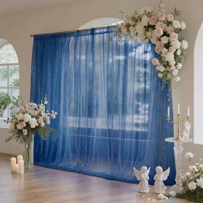 Elegant wedding backdrop with blue sheer curtains, flowers, and candles
