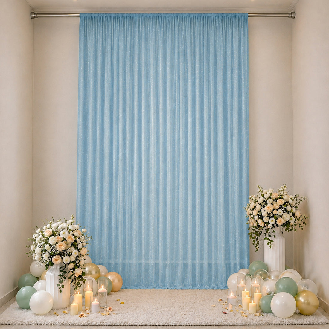 Elegant baby shower backdrop with blue curtain, floral arrangements, and pastel balloons