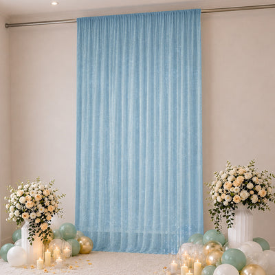 Blue sheer curtain backdrop with balloons, floral arrangements, and candles
