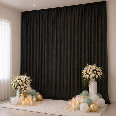 Elegant black backdrop with floral arrangements, candles, and pastel balloons