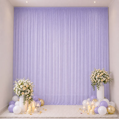Lavender party backdrop with floral stands, balloons, and candles for celebration