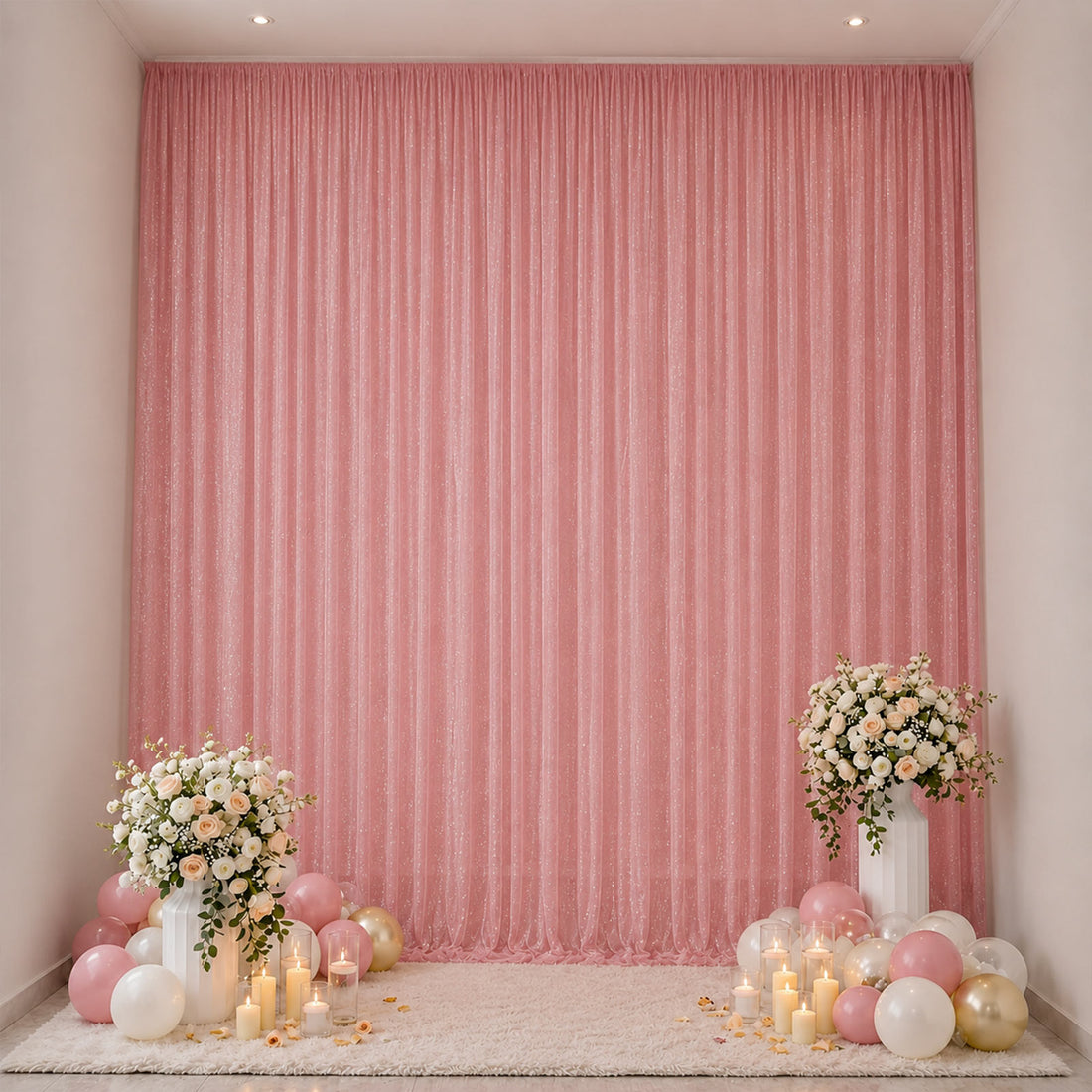 Pink party backdrop with floral arrangements, candles, and balloons in a decorated room