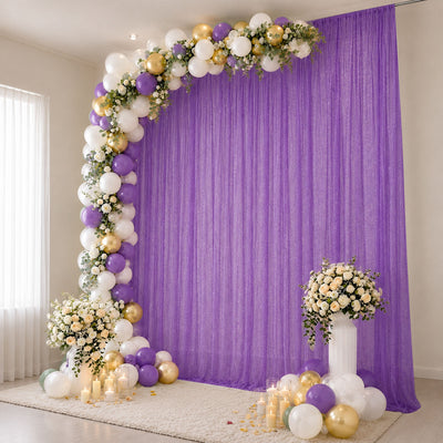 Purple and gold balloon arch with floral backdrop and candles for elegant event decor