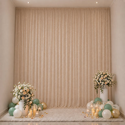 Elegant floral and balloon party backdrop with candles and soft beige drapes