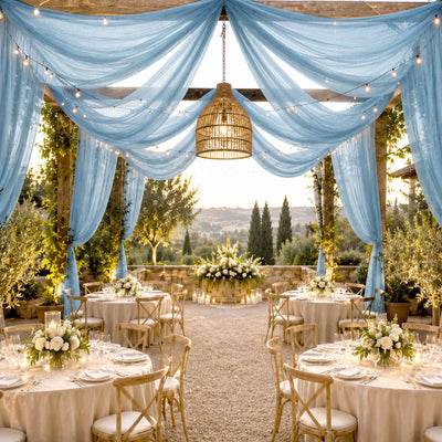 Elegant outdoor wedding reception with blue drapery, string lights, and floral tablesetting