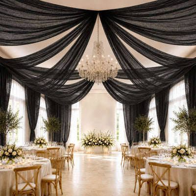 Elegant black draped wedding reception with chandelier and floral centerpieces