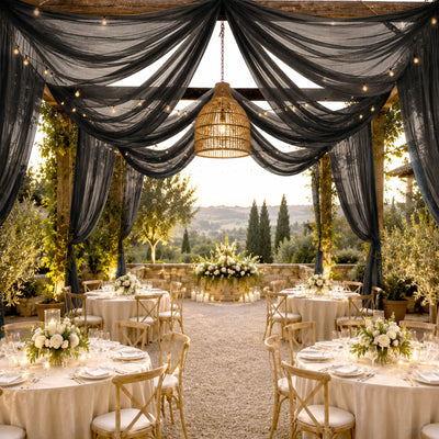 Elegant outdoor wedding reception with black drapery, string lights, and floral tablescape