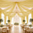 Elegant wedding reception with gold draped ceiling, chandelier, and floral tables