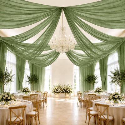 Elegant wedding reception with green drapery, chandelier, and floral tablescape