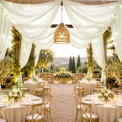 Elegant outdoor wedding reception with draped white canopy and floral tablescapes