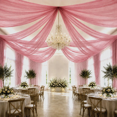 Pink draped wedding reception hall with chandelier and elegant floral tables