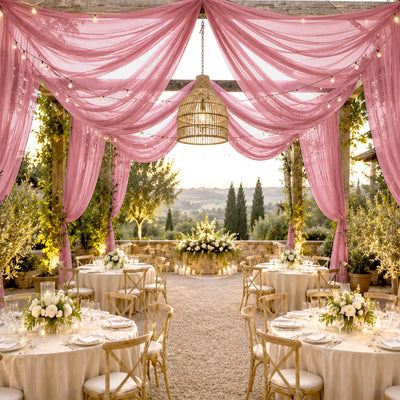 Elegant outdoor wedding reception with pink drapery, string lights, and floral tables.