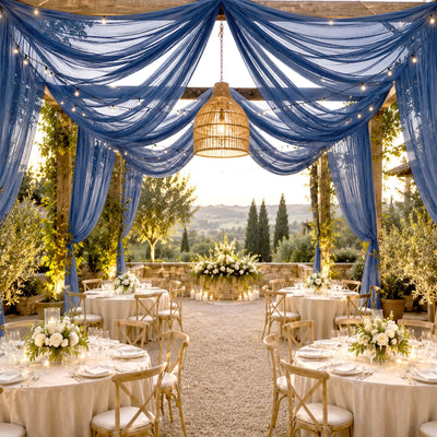 Elegant outdoor wedding reception with blue drapes, string lights, and rustic tables