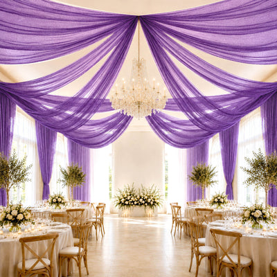 Elegant purple draped wedding reception with chandelier and floral centerpieces