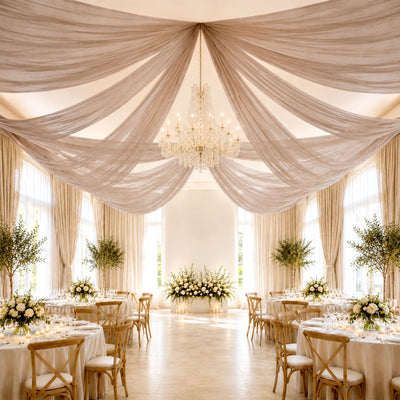 Elegant wedding reception hall with draped ceiling, chandelier, and floral tables