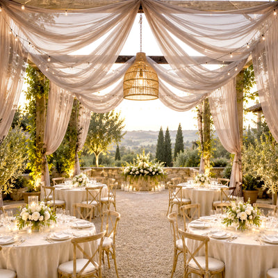 Elegant outdoor wedding reception with draped canopy, floral tables, and sunset view