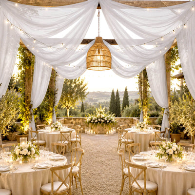 Elegant outdoor wedding reception with white drapery, fairy lights, and rustic tables