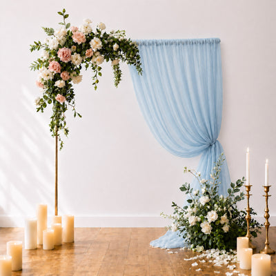 Elegant floral wedding arch with blue drape and candles in a modern venue