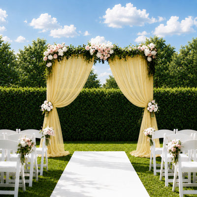 Outdoor garden wedding arch with flowers, drapes, and white chairs