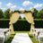 Outdoor garden wedding arch with flowers, drapes, and white chairs
