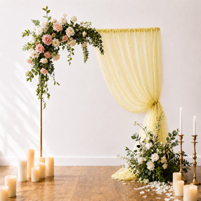Elegant wedding floral arch with draped yellow curtain and candles