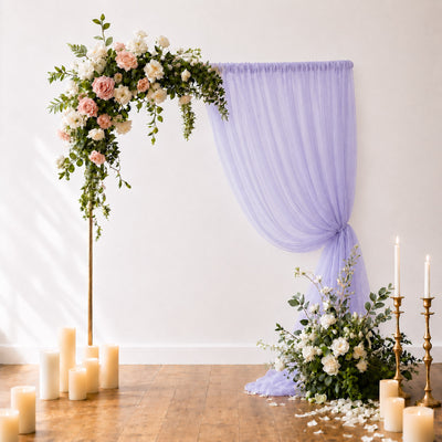 Elegant floral wedding arch with lavender drapery and candles