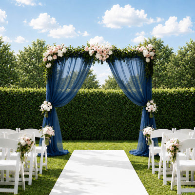 Elegant outdoor wedding arch with blue drapes, flowers, and white chairs