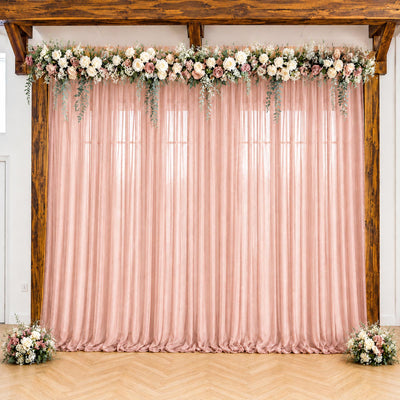 Pink wedding backdrop with floral garland, draped curtains, and wooden arch frame