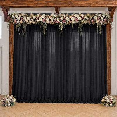 Rustic wedding backdrop with black drapes, floral garland, and wooden frame