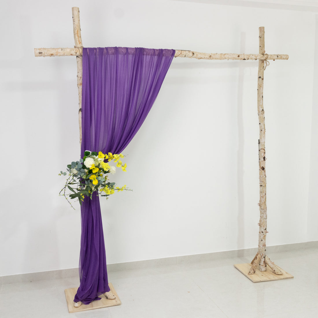 Purple drapery and floral arrangement on a rustic wooden frame
