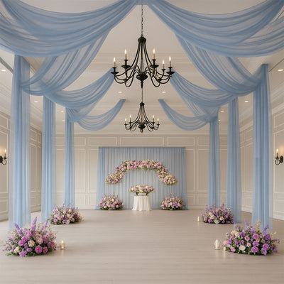 Elegant wedding venue with blue drapery and floral arrangements.