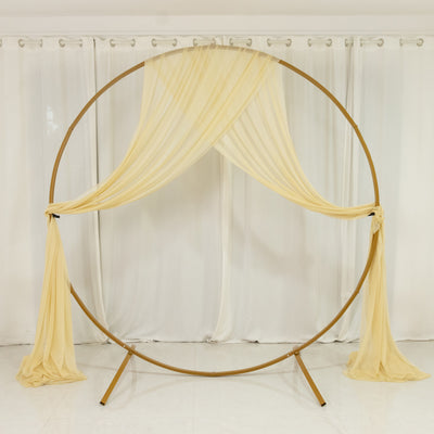 Golden wedding arch with flowing yellow drapes on a white backdrop.