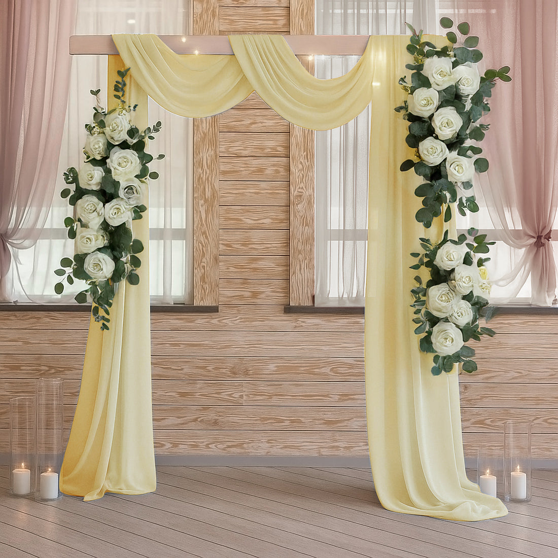 Elegant wedding arch with yellow drapes and white roses, set in a cozy venue.