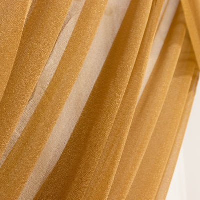 Gold pleated fabric texture with sheer striped drapes close-up