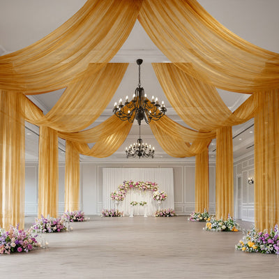 Elegant wedding reception hall with gold drapes, chandeliers, and floral decor