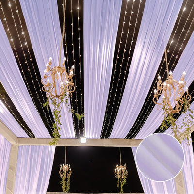 Elegant draped fabric with chandeliers and fairy lights for event decor.
