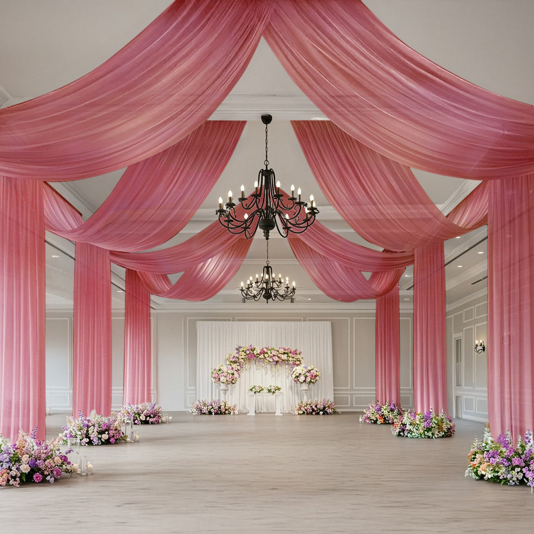 Elegant wedding venue decorated with pink drapes and floral arrangements.