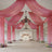 Elegant wedding venue decorated with pink drapes and floral arrangements.