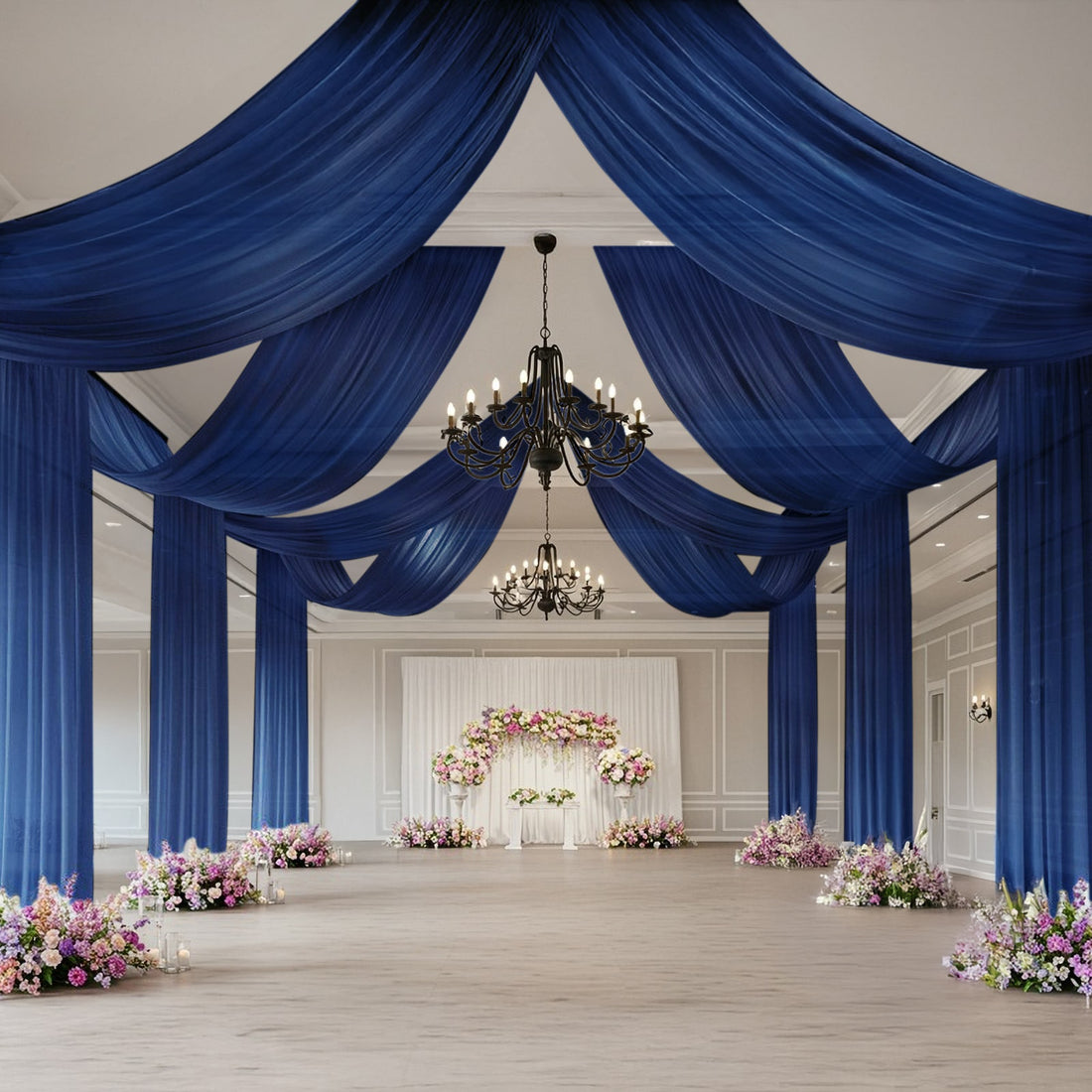 Elegant event space with blue drapery and floral arrangements.