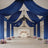 Elegant event space with blue drapery and floral arrangements.