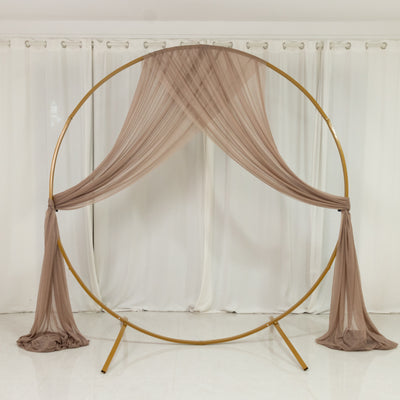 Gold circular backdrop stand with flowing brown drapery.