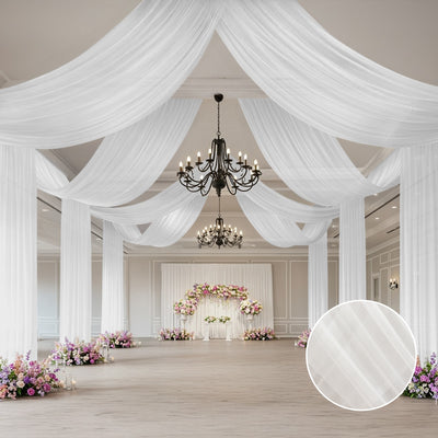 Elegant white drapery in a decorated event space with chandeliers and floral arrangements.