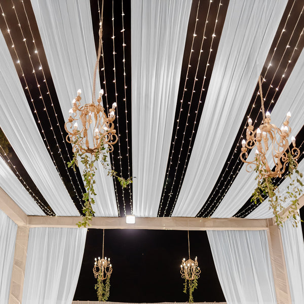 Elegant chandeliers and draped fabric ceiling at an event venue.