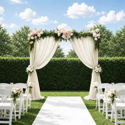 Outdoor wedding ceremony arch with white drapes, pink roses, and garden seating