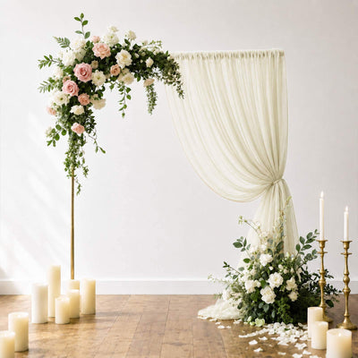 Elegant wedding floral arch with draped ivory curtain and candles